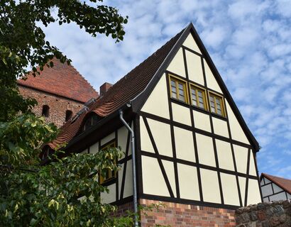 Blick auf das Museum Pasewalk an der Stadtmauer. Ein Gebäude im Fachwerkstil und dahinter das Prenzlauer Tor.