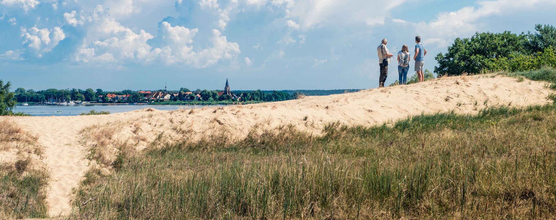 Drei Menschen stehen auf der Düne am Stettiner Haff