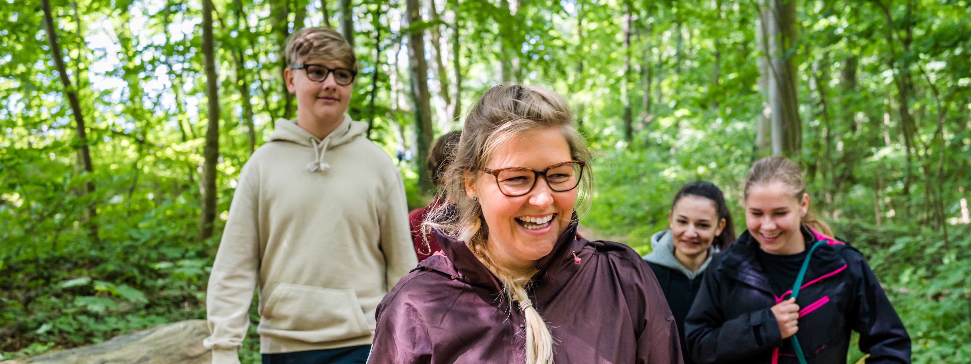 Five people with a smile on the face in the forest.