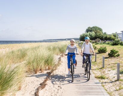 Zwei Personen fahren auf einem Weg am Strand von Lubmin.