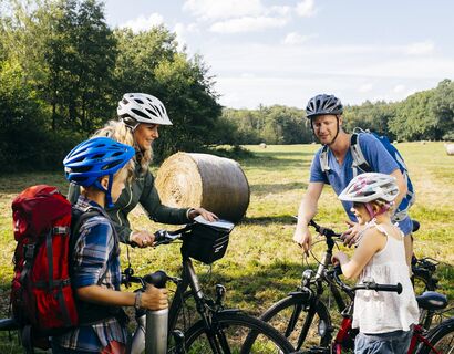 Kurzer Stopp zur Orientierung im Müritz-Nationalpark Eine Familie steht mit ihren Fahrräder am Rand eines Feldes und berät sich.