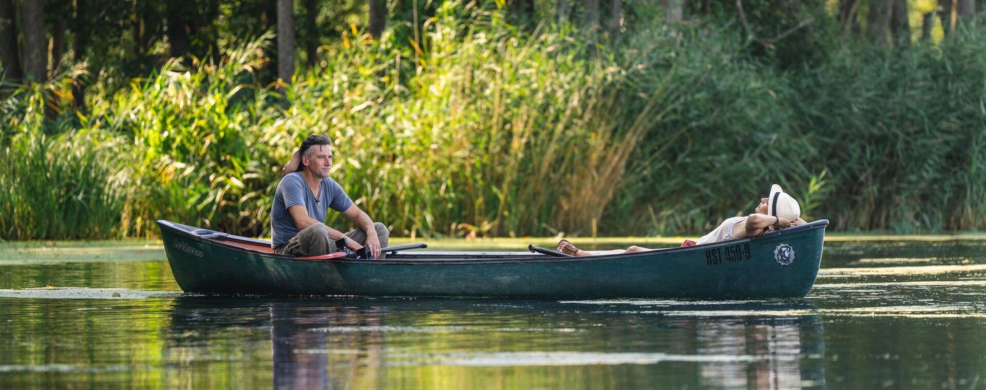 Zwei Personen lassen sich in einem Paddelboot auf der Peene treiben.