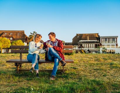 A couple sits on a bench and encounters with a drink.