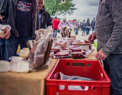 verschiedener eingeschweißter Schinken und eine rote Kiste an einem Stand