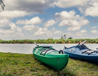 The focus is on three canoes two blue and a green one from right to left. Water in the background