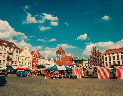 View of the marketplace in Greifswald with the red and white striped market tents and chain carousel