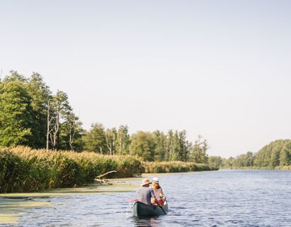 Ein Mann und ein Frau sitzen in einem Kanu und paddeln auf der Peene