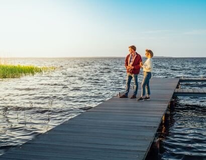 Couple stands on a jetty and looks at the sun