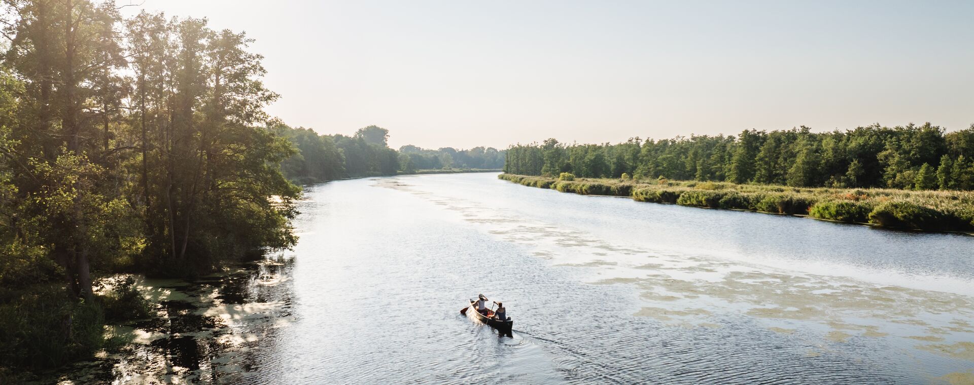 Two people sit in one canoe and paddle along the Peene