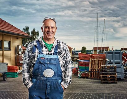 The fisherman Dirk Baumann with blue dungarees over a blue and white-checked flannel shirt.