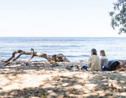 A man and a woman sit on the beach in Vierow and look at the sea