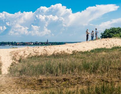 Drei Menschen stehen auf der Düne am Stettiner Haff