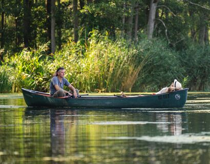 Zwei Personen lassen sich in einem Paddelboot auf der Peene treiben.