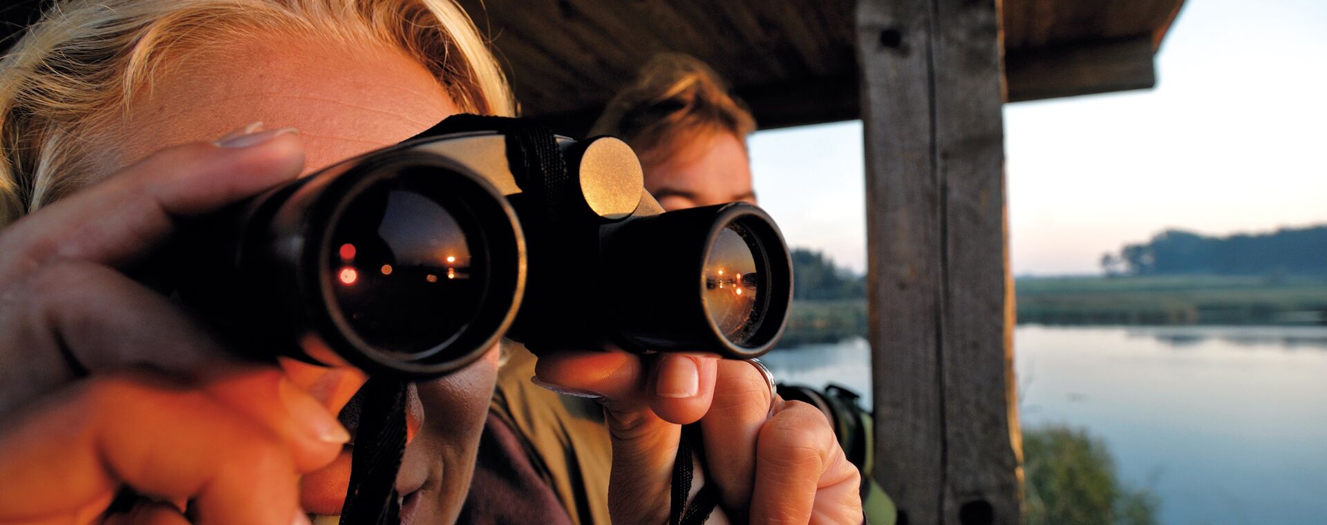 A woman looks through a binoculars at a viewpoint