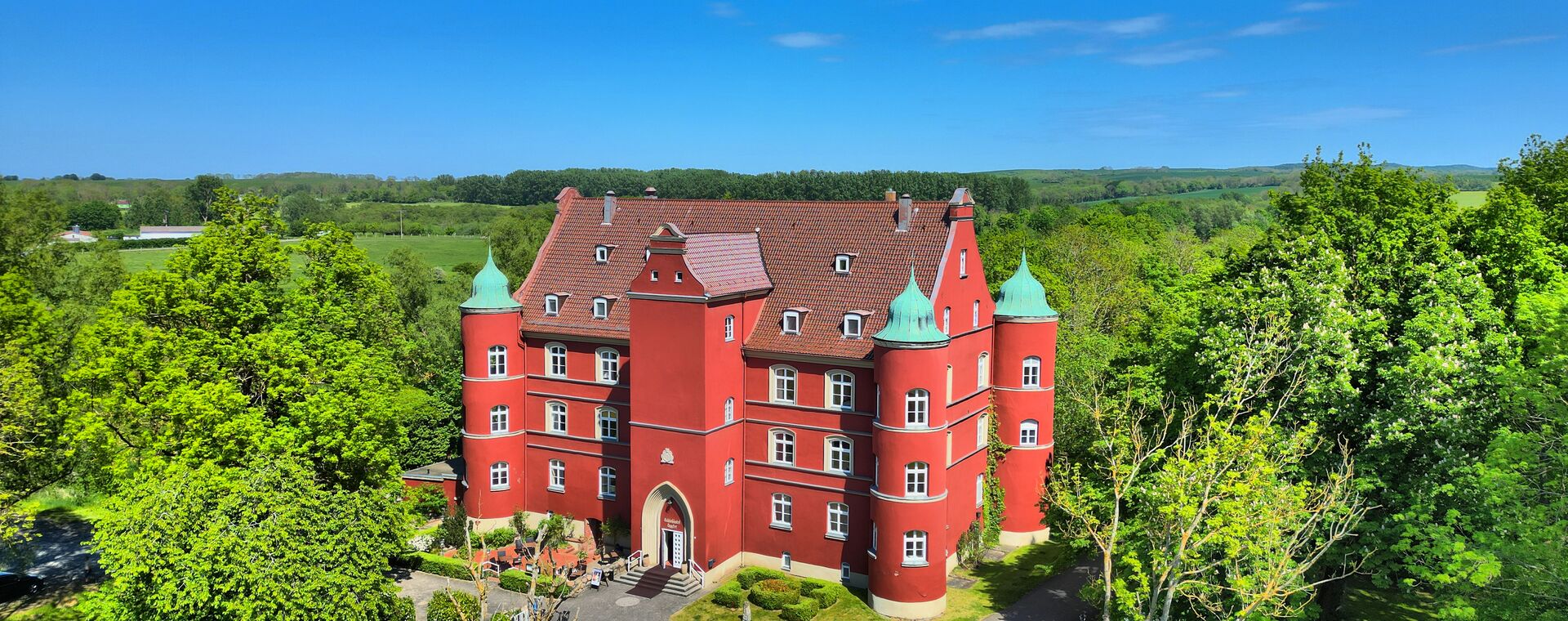 Ein rotes Schloss ist umringt von Bäumen.