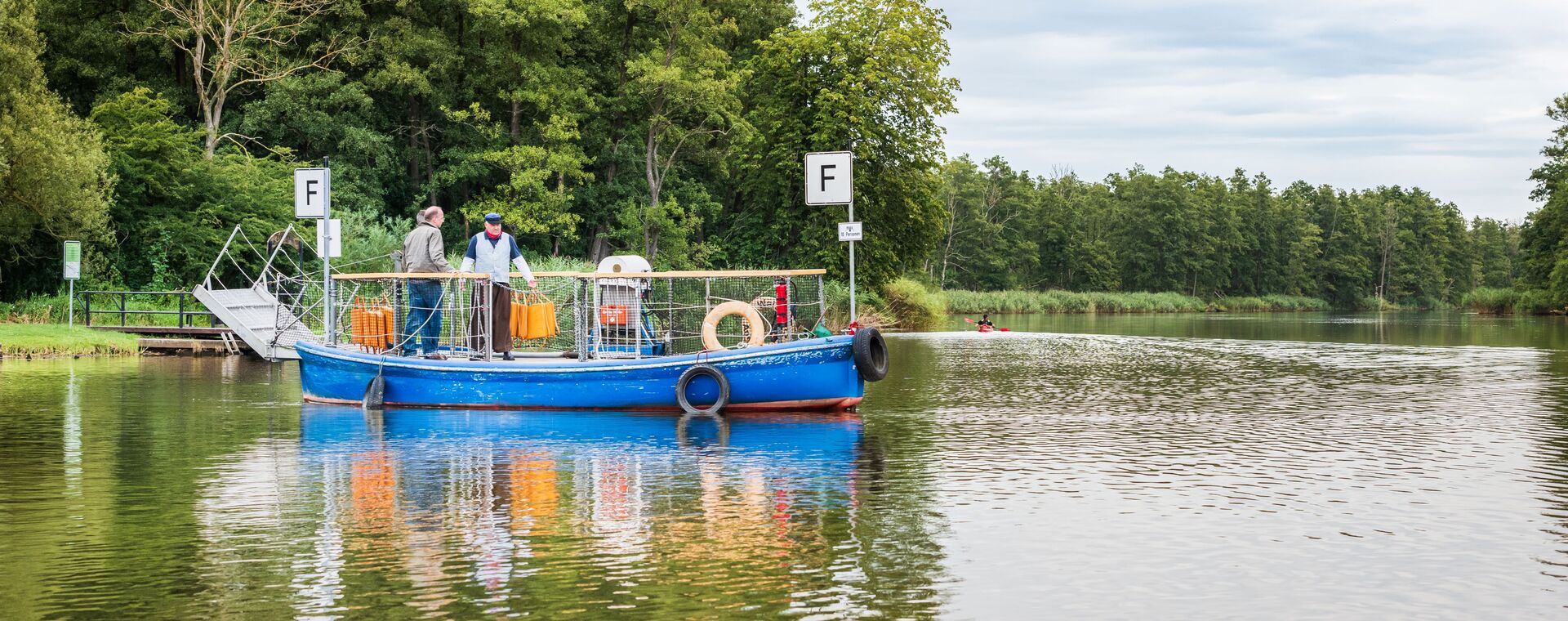 The blue passenger and bicycle ferry translated via the Peene