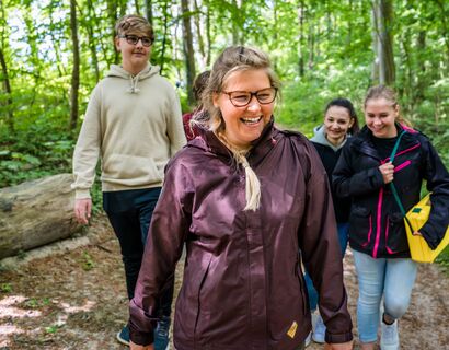 Fünf Personen mit Lächeln im Gesicht im Wald.