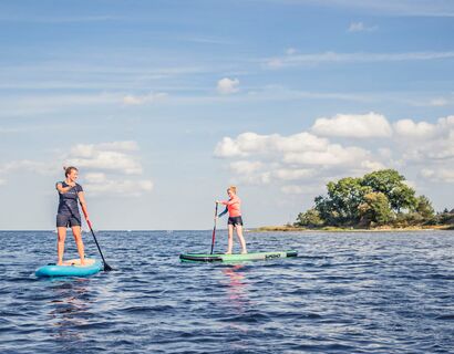 In the distance, two women paddle standing on the SUP.