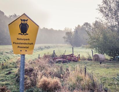 Ein gelbes Schild, mit der Bewschriftung "Naturpark Flusslandschaft Peenetal"