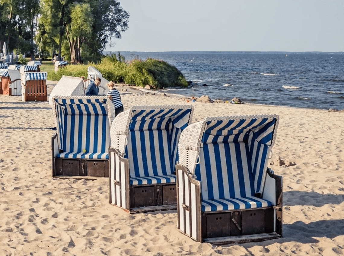 Three blue and white striped beach chairs on the beach of Altwarp