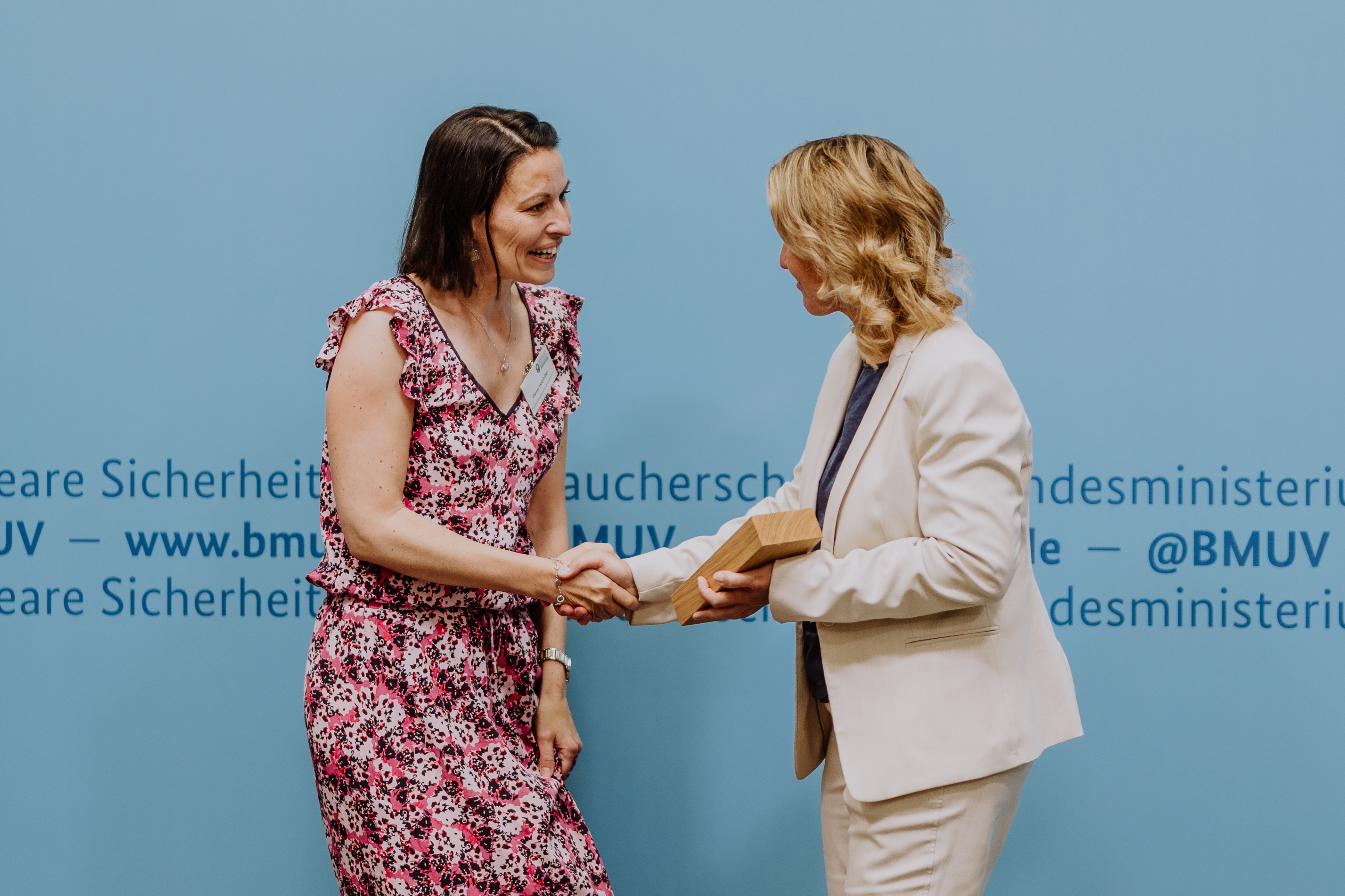 Fanny Holzhüter bekommt den Preis für den ersten Platz von Bundesumweltministerin Steffi Lemke überreicht, sie schütteln sich die Hände.